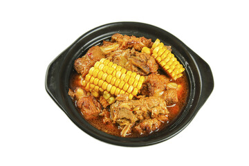 Braised Pork Ribs with Corn on the Cob in Black Pot on White Background