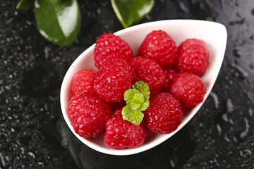 Fresh Red Raspberries in White Bowl with Mint Leaf on Dark Background