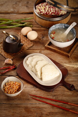 Traditional Asian steamed buns with cooking ingredients on wooden table - authentic Chinese cuisine preparation
