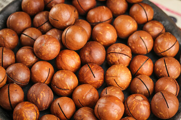 Roasted Macadamia Nuts from Yunnan China with Cracked Shells Showing Creamy White Kernels Inside