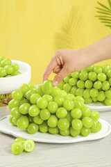 Fresh Green Seedless Grapes on Plate with Hand Reaching - Healthy Fruit Snack