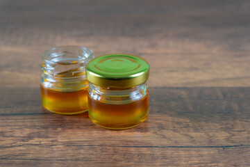 A small golden honey jar was placed on a wooden table.