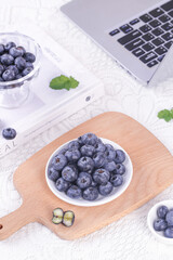 Fresh Yunnan Alpine Blueberries on Wooden Board with Laptop - Healthy Workspace Snack