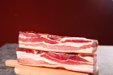 Raw Smoked Bacon Strips with Marbled Fat on Wooden Cutting Board