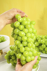 Fresh Green Grapes in Hands on Bright Yellow Background - Healthy Fruit Concept