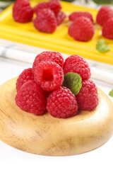 Fresh Red Raspberries on Wooden Plate with Shallow Depth of Field and Dessert Background