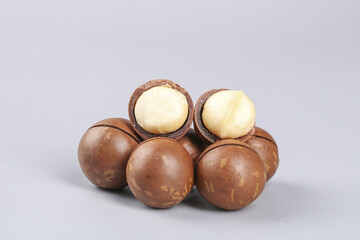 Fresh Macadamia Nuts with Cracked Shells Showing Creamy White Kernels on White Background