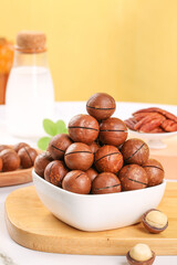 Fresh Macadamia Nuts in White Bowl on Wooden Counter Display with Milk Bottle Background