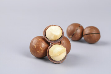 Macadamia Nuts with Cracked Shells Showing Creamy Kernels on White Background