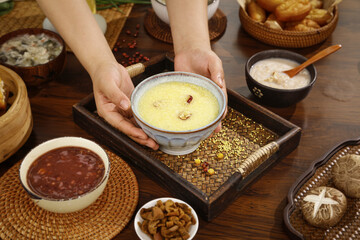 Traditional millet porridge in hands with Asian breakfast foods and grains on wooden table top view