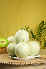 Fresh Honeydew Melons on Plate with Palm Leaves Yellow Background Healthy Organic Fruit Display