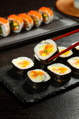 Japanese Sushi Rolls with Seaweed and Rice on Slate Platter - Traditional Asian Cuisine with Chopsticks