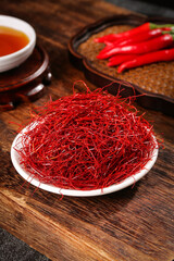 Dried Shredded Red Chili Peppers in Bowl on Wooden Table with Fresh Peppers and Tea Cup