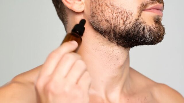Man applying oil to beard with dropper bottle
