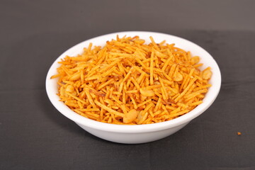 Aloo or alu chivda or chiwda. A healthy and delicious snack with fried grated potatoes with cornflower coating and nuts served in traditional bowl. A snacks for fast in Indian culture.
