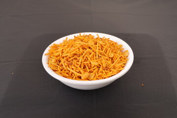 Aloo or alu chivda or chiwda. A healthy and delicious snack with fried grated potatoes with cornflower coating and nuts served in white bowl. A snacks for fast in Indian culture.