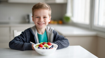 Smiling boy eating healthy breakfast with fresh fruits in bright kitchen.
