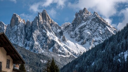 Fototapeta premium Snowy mountain peaks rise above a valley, with a glimpse of a village nestled at the base