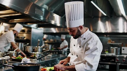 A bustling kitchen scene captured from a side angle, showcasing chefs in action. The video highlights culinary expertise and teamwork in a professional setting.