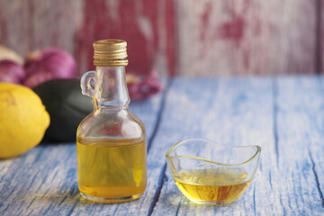 Glass bottle and bowl filled with olive oil accompanied by fresh produce