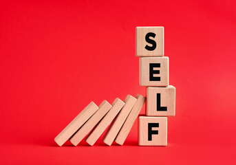 Self destruction concept. Dominoes demolishing the wooden cubes with the word self.