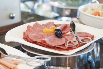 Sliced deli meats served on a plate with garnishes