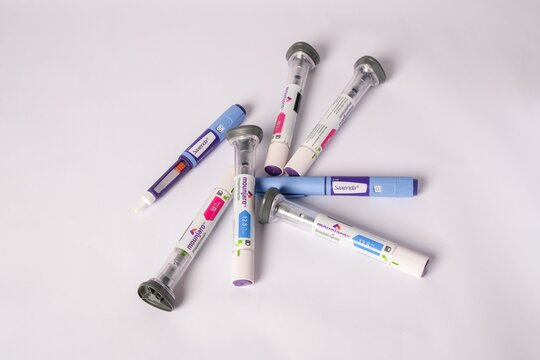 Top view of various medical injection pens on a white background showcasing healthcare tools.