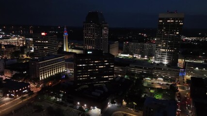 Lighting city skyline of Springfield, Massachusetts’s at night. Mirrored high-rise buildings and skyscrapers. Traffic on road in background. Downtown scene in American town. Aerial wide shot.
