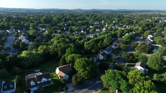 Quiet and quaint suburb neighborhood of American town. Sunset time in the evening. Aerial wide shot. Green trees in upper class district. Houses and homes in Lititz, Pennsylvania.