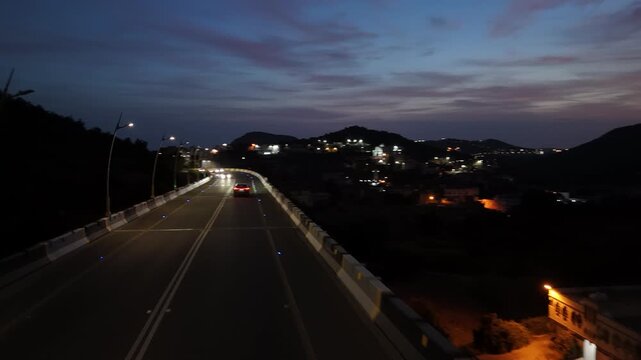 Aerial view of a black car driving on a illuminated elevation road in Saudi Arabia