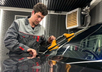 Automobile special workers replacing windscreen or windshield of a car in auto service station garage. Glass of the car, removed with the help of professional suction cups. The process of car repair. 