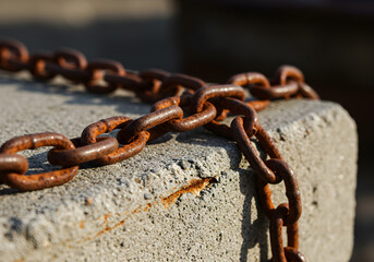 Weathered iron chain rests on textured concrete under warm light, evoking history and resilience