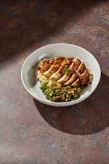 Ptitim with chicken fillet, bright natural light, overhead plating on rustic earthenware