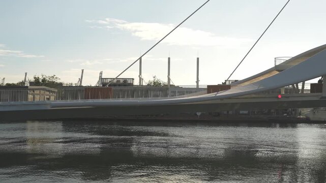 Modern pedestrian bridge over calm waterfront against clear sky at sunset