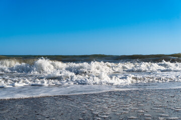 Blue sea and large waves and foam. Storm Wave splashing over pebbles at sea. Rolling ocean waves. Summer paradise beach background. Powerful sea waves