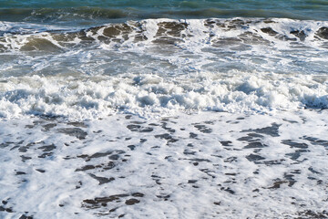 Blue sea and large waves and foam. Storm Wave splashing over pebbles at sea. Rolling ocean waves. Summer paradise beach background. Powerful sea waves