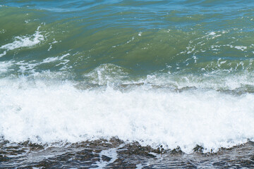 Blue sea and large waves and foam. Storm Wave splashing over pebbles at sea. Rolling ocean waves. Summer paradise beach background. Powerful sea waves