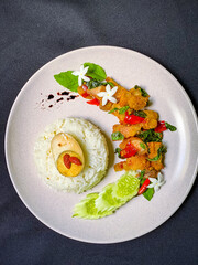 Spicy Thai stir-fry with crispy pork belly and fragrant holy basil, served with rice for a flavorful street food favorite.