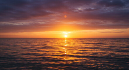 Fototapeta premium Stunning sunset over ocean with vibrant golden light reflecting off the water is so calming and peaceful