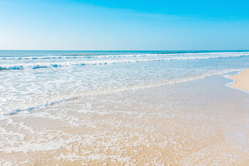 Summer Ocean Waves Gently Washing onto Sandy Shore at Sunset