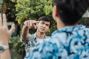 A brave young Southeast Asian man forcefully points at his smirking bully in an emotionally intense standoff, showing zero tolerance for intimidation.