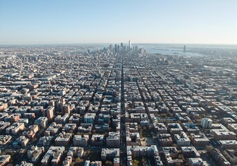 Panoramic aerial view of a sprawling metropolis city grid with distant skyscrapers under clear sky.
