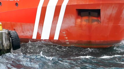 Large red ship near dock in the harbor