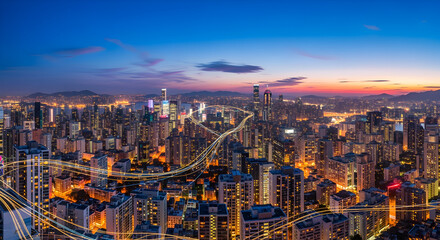 Obraz premium Aerial View of Dense Urban Cityscape at Dusk with Illuminated Buildings and a Gradient Blue Pink Skyline