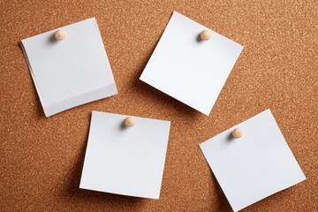 Empty white and brown sticky notes pinned on a corkboard for reminders, planning, organization, or creative workspace concepts.
