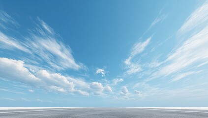 Wide shot of a paved surface extending into a vast, light blue sky dotted with wispy clouds