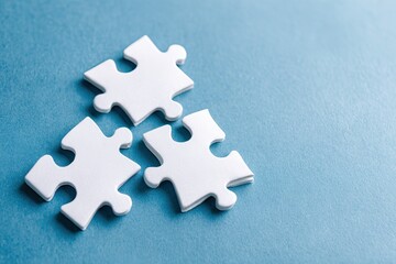 Obraz premium Three white puzzle pieces on a light blue surface