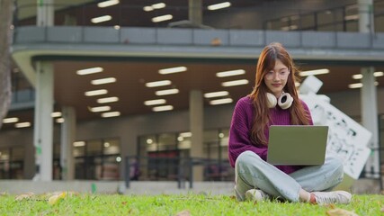 Close-up of one university student playing with a smartphone outside a classroom building in a walkway.