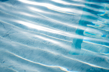Bright light blue water surface with shimmering wave reflections, abstract liquid texture