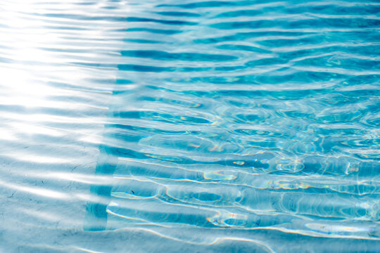 Bright light blue water surface with shimmering wave reflections, abstract liquid texture